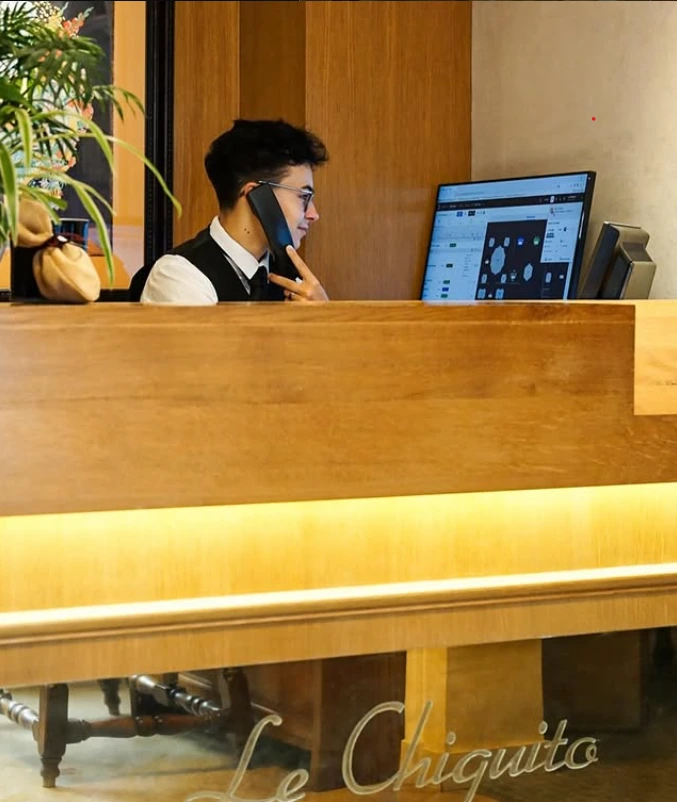Membre de l'équipe du restaurant Le Chiquito au téléphone à l'accueil, derrière le comptoir en bois